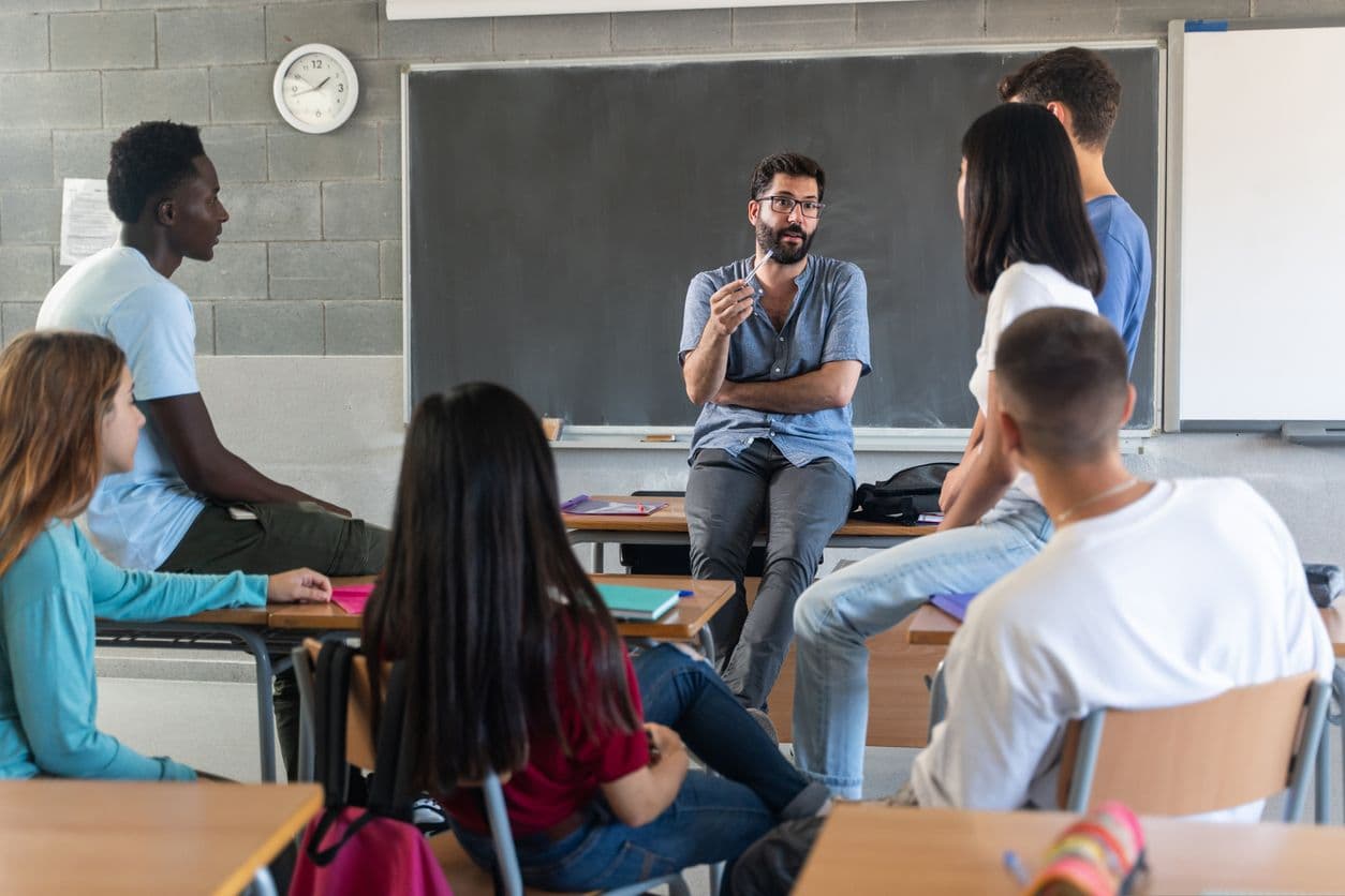 A group of students attentively sitting at desks in a classroom, engaged in learning activities.